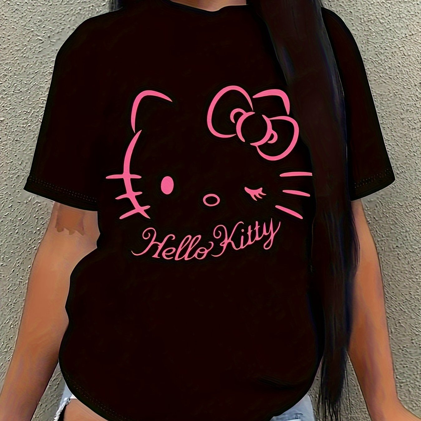 Hello Kitty Pink Bow Black Graphic Women's T-shirt styled with casual wear, featuring a bold pink Hello Kitty graphic on a black background.